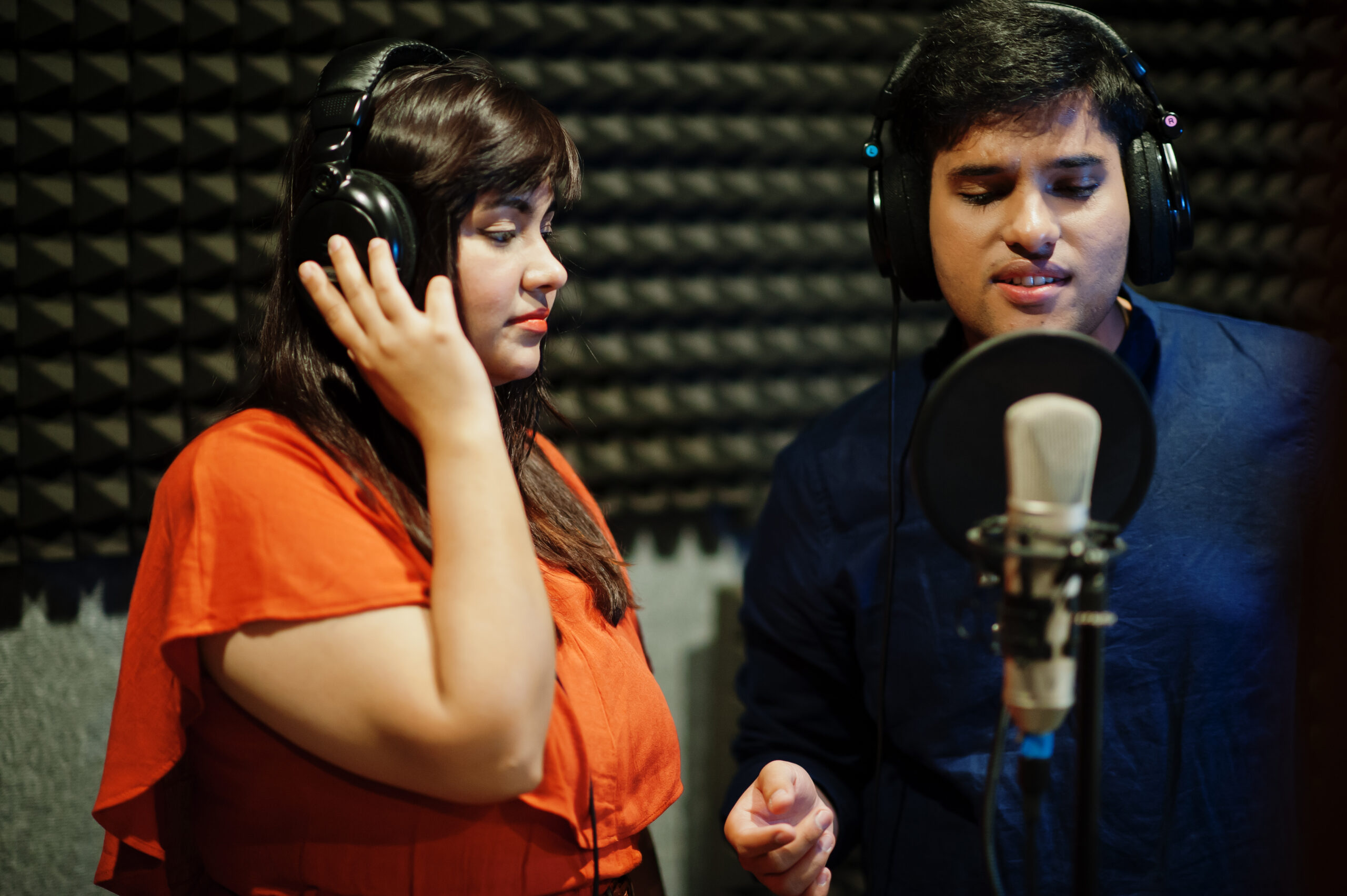 young asian duet singers with microphone recording song in recor